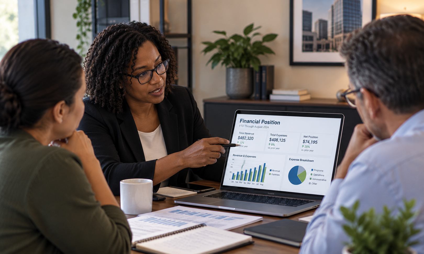 Three professionals discussing a financial dashboard and reports at an office table.